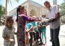 
An Iraqi citizen hands out guidebooks to children on how to avoid the dangers of mines and how to avoid approaching or playing with unknown objects. Photo posted on April 4, 2022. [Iraqi Ministry of Environment]        