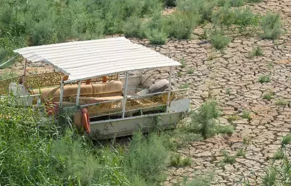 A dilapidated boat is grounded on a dried-up strip of Lake Habbaniyah, August 11, a result of severe drought in Iraq's Anbar province. [Murtadha Ridha/AFP]