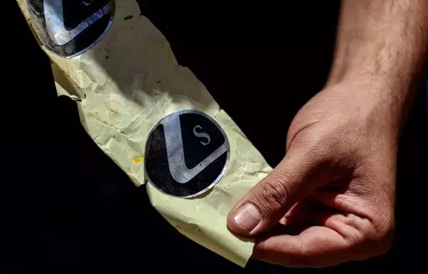 A Lebanese security official holds a set of confiscated stickers used for the branding of a particular Captagon pill manufacturer at the judicial police headquarters in the city of Zahle in Lebanon's Bekaa Valley on July 21, 2022. [Joseph Eid/AFP]