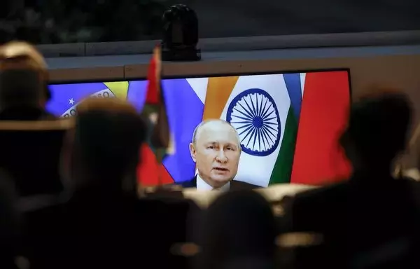 A screen shows Russian president Vladimir Putin virtually delivering remarks as delegates look on while attending a meeting during the 2023 BRICS Summit in Johannesburg on August 24. [Marco Longari /POOL/AFP]