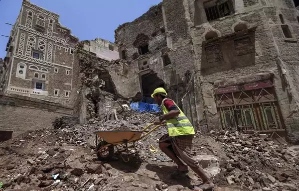 A worker removes the rubble to prepare for restoration on the site of a collapsed UNESCO-listed building following heavy rains, in the old city of Sanaa, on August 12, 2020. [Mohammed Huwais/AFP]