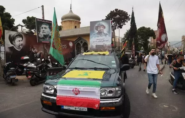 A vehicle displays the flags of Iran and Hizbullah as it moves in a funerary procession for a fallen fighter in Beirut's southern suburb on August 10, after he was killed the previous day amidst clashes between Hizbullah and residents of the Christian town of Kahale in Mount Lebanon. [Anwar Amro/AFP]