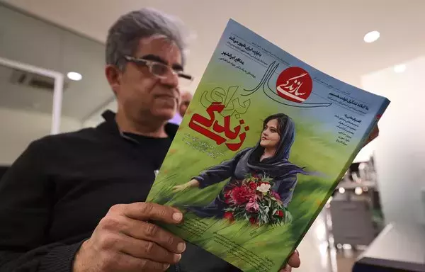 رجل يحمل في طهران بتاريخ 14 آذار/مارس نسخة من مجلة سازانديجي الإيرانية تناولت قضية مهسا أميني التي توفيت بعد اعتقالها على يد ʼشرطة الآدابʻ. [عطا كيناري/وكالة الصحافة الفرنسية]