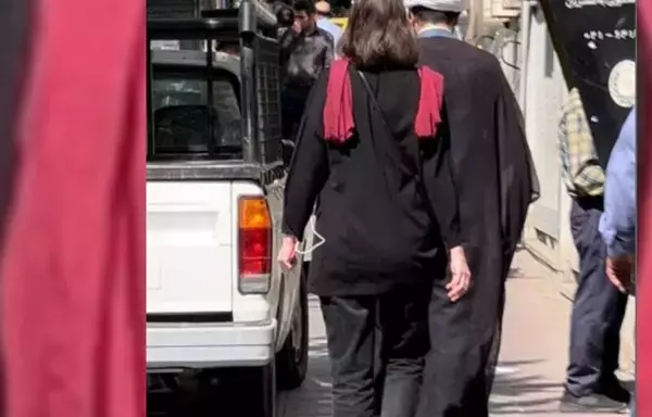 A young woman follows a cleric on a street in Iran. Some young women have been mocking clerics on Iranian streets since the 2022 protests started. [Social media via Bozorgmehr Hassanpour]