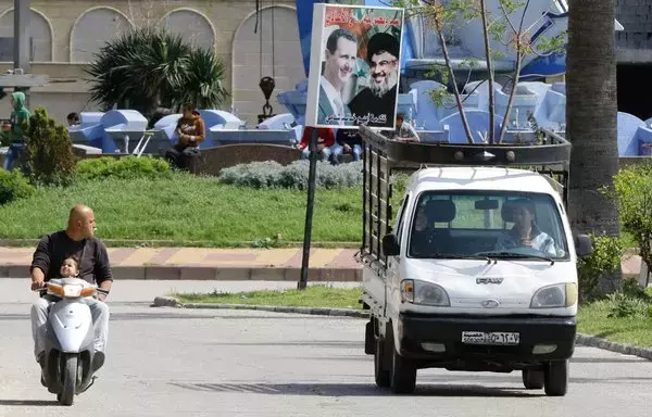 A poster with portraits of Syrian president Bashar al-Assad and Hizbullah chief Hassan Nasrallah is seen in the coastal city of Latakia, the heartland of the Syrian president's Alawite sect, on March 17, 2016. More recently, anti-regime sentiment has been on the rise in the area, local activists say. [Louai Beshara/AFP]