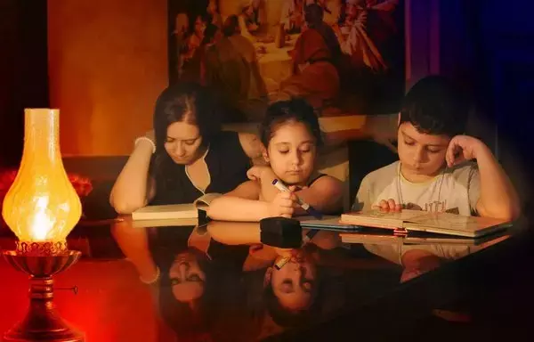 Schoolchildren in Lebanon study at home by lantern light. [Naji Akram/Al-Fassel]