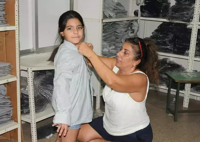 A girl tries on a school uniform ahead of the 2023-2024 school year. [Naji Akram/Al-Fassel]