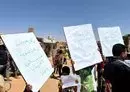 
Al-Rukban camp residents hold signs denouncing the Syrian regime on September 1 in solidarity with the ongoing protests in the southern city of Sweida. [Al-Rukban Media Center]        