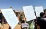 
Al-Rukban camp residents hold signs denouncing the Syrian regime on September 1 in solidarity with the ongoing protests in the southern city of Sweida. [Al-Rukban Media Center]        