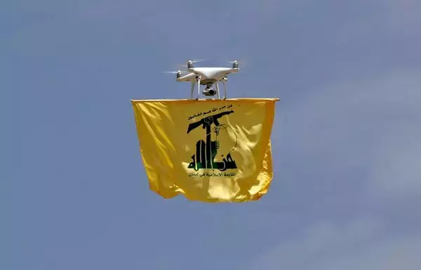 A drone carries the flag of Lebanese Hizbullah above Aarmata bordering Israel on May 21. The Iran-backed party simulated cross-border raids into Israel in a show of its military might, using live ammunition and an attack drone. [Anwar Amro/AFP]