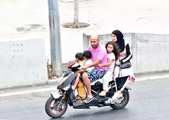 A man drives his wife and three children through Beirut on a motorcycle. For some in Lebanon, the high cost of fuel has put the cost of running a car out of reach. [Naji Akram/Al-Fassel]