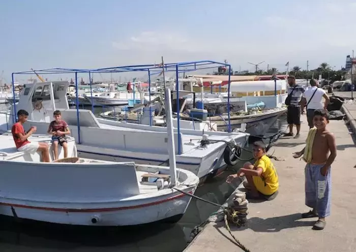 Children play on boats in the northern port of Tripoli. The severe economic crisis has forced many children to drop out of school because their parents are unable to pay the high tuition fees. [Naji Akram/Al-Fassel]