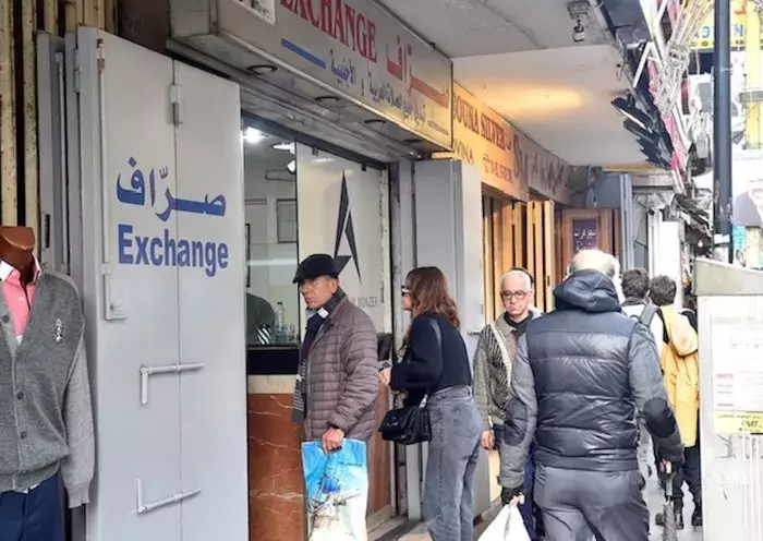 People line up to convert currency outside a money exchange shop in Beirut. Since the outbreak of the economic crisis in Lebanon, the exchange rate of the pound against the dollar has plummeted. [Naji Akram/Al-Fassel]