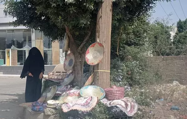 Umm Farhan has set up shop on Sanaa's al-Khamseen street, where she sells handcrafted baskets made by another woman. [Yazan Abdul Aziz/Al-Fassel]