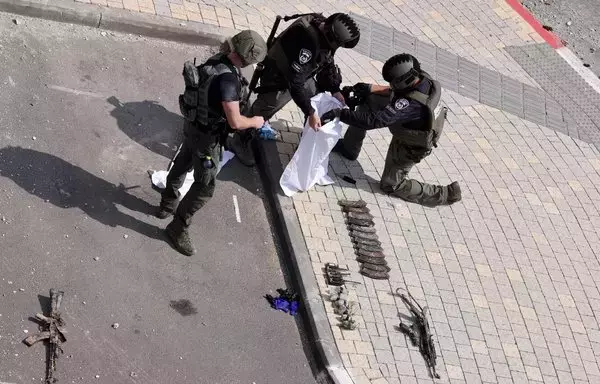 Israeli soldiers inspect the weapons used by their foes in front of an Israeli police station in Sderot, on October 8, after battles to dislodge Hamas militants who were stationed inside. [Jack Guez/AFP]