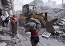 
A Palestinian man carries salvageable items as civilians and rescuers help clear the rubble in the heavily bombarded city center of Khan Yunis in the southern Gaza strip following overnight Israeli shelling, on October 10. [Said Khatib/AFP]        