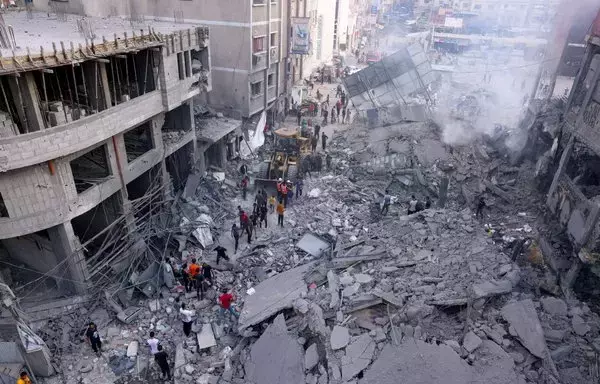 Palestinian civilians and rescuers help clear the rubble in the heavily bombarded city center of Khan Yunis in the southern Gaza strip following overnight Israeli shelling, on October 10. [Said Khatib/AFP]