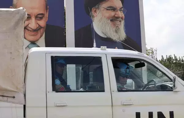 A United Nations Interim Forces in Lebanon patrol drives past portraits of Hizbullah chief Hassan Nasrallah (R) and Parliament Speaker Nabih Berri, of the Amal movement, in the southern Lebanese village of Adaisseh along the border with Israel on October 10. [Joseph Eid/AFP]