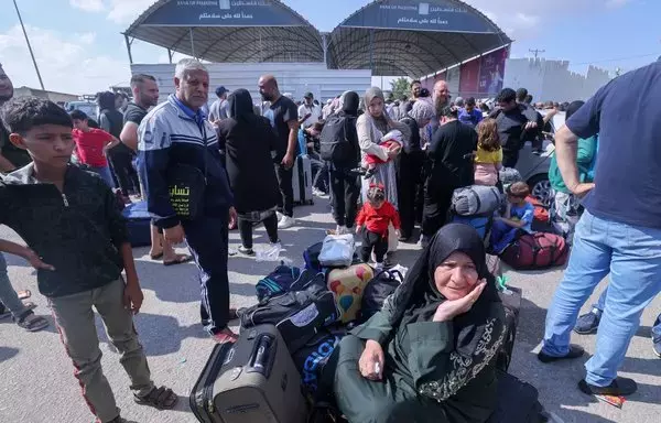 Palestinians, some with foreign passports hoping to cross into Egypt and others seeking aid, wait at the Rafah crossing in the southern Gaza strip on October 16. [Mohammed Abed/AFP]