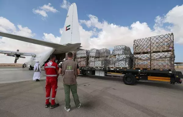 عمال يفرغون المساعدات لقطاع غزة من طائرة بضائع إماراتية على المدرج في مطار العريش المصري في شمال سيناء يوم 19 تشرين الأول/أكتوبر. [غوزيبي كاكاتشي/وكالة الصحافة الفرنسية]