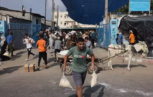 فلسطينيون يقتحمون مركز إمدادات مساعدات تديره الأمم المتحدة في مدينة دير البلح بوسط قطاع غزة ويوزع الغذاء على الأسر النازحة، وذلك وسط المعارك المتواصلة بين إسرائيل وحركة حماس. [محمد عابد/وكالة الصحافة الفرنسية]