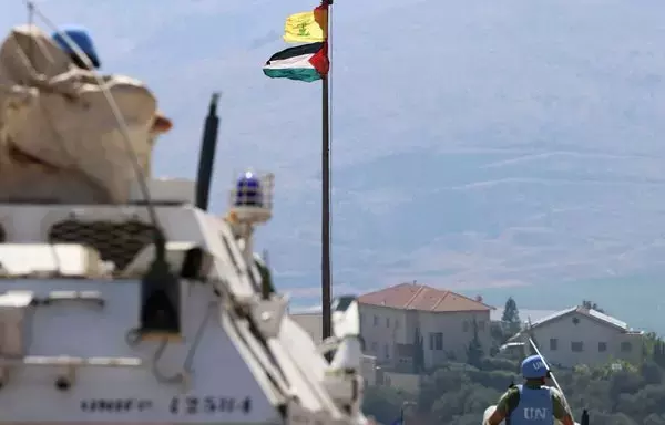 The Palestinian flag and the flag of Hizbullah wave in the wind on a pole as peacekeepers from the United Nations Interim Force in Lebanon patrol the border area between Lebanon and Israel on Hamames hill in the Khiyam area of southern Lebanon on October 13. [Joseph Eid/AFP]