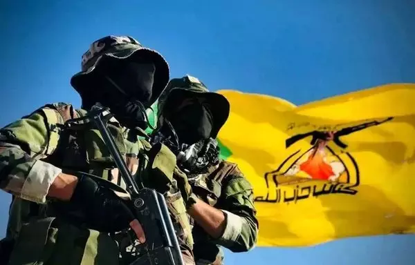 Two heavily armed fighters from the Iran-backed Iraqi militia Kataib Hizbullah are seen here with the militia's flag in an undated photo circulated on social media. The militia announced it has joined the Israel-Hamas war alongside the Palestinian militant group Hamas.