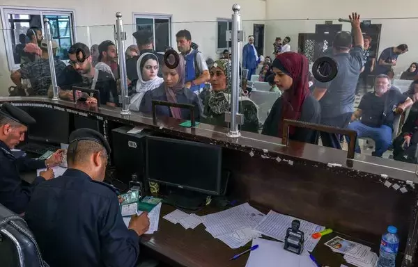 Palestinian border guards check the documents of people leaving Gaza as dual national Palestinians and foreigners prepare to cross the Rafah border point with Egypt on November 2. [Said Khatib/AFP]