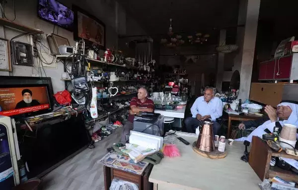 People sitting in a shop watch the televised speech of Lebanon's Hizbullah chief Hassan Nasrallah in the occupied West Bank town of Tubas on November 3. Nasrallah on November 3 spoke for the first time since war broke out between Hamas and Israel. [Jaafar Ashtiyeh/AFP]