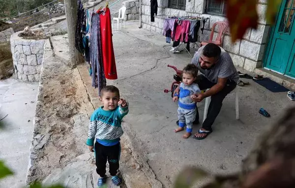 Syrian refugee Hassan al-Ali, 26, who was separated from his pregnant wife on a migrant boat heading to Cyprus, plays with their children Khaled, 3, and Fatima, 2, at their house in Ain el-Tefaha, east of Beirut, on September 23, 2021. [Joseph Eid/AFP]