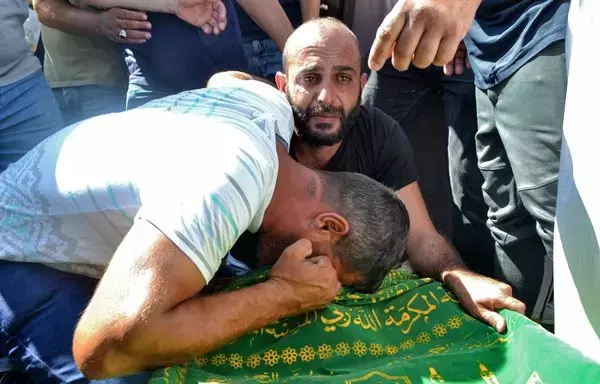 Mourners react by the body of a victim who drowned when a migrant boat sank off the Syrian coast, during his funeral in the Nahr al-Bared refugee camp, on the outskirts of Tripoli, Lebanon, on September 24, 2022. At least 77 migrants drowned when a boat they boarded in Lebanon sank off Syria's coast, in one of the deadliest such shipwrecks in the eastern Mediterranean. [Fathi al-Masri/AFP]