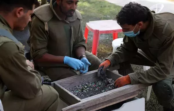 Israeli soldiers on November 9 help archaeologists from the Israel Antiquities Authority sift through ashes from burnt out dwellings inside Kibbutz Nir Oz in southern Israel, to identify residents who went missing during the October 7 terrorist attack. [Gil Cohen-Magen/AFP]