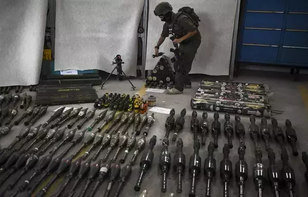 An Israeli soldier stands with weapons recovered from areas Hamas targeted in its October 7 terrorist attack on southern Israel, on October 26. [Aris Messinis/AFP]