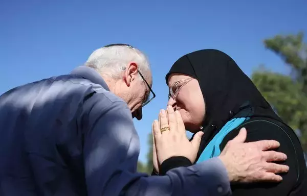 Nir (L), the brother of killed Israeli-Canadian peace activist Vivian Silver, greets Arab-Israeli Ghadir Hani, a fellow peace activist from Acre, during a memorial service for Silver in Kibbutz Gezer, in central Israel on November 16. [Oren Ziv/AFP]