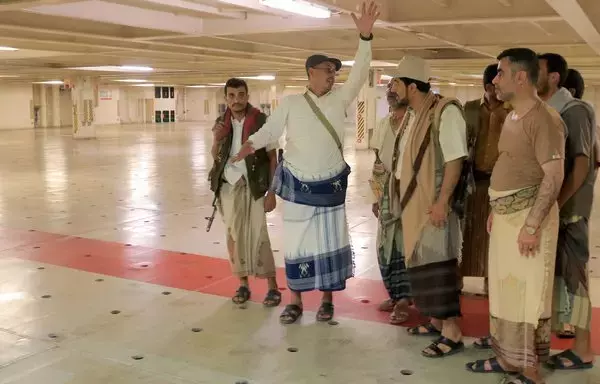 A picture taken November 22 during a tour organized by the Houthis shows the group's minister of information, Dhaifallah Al-Shami (2nd L), inspecting the Galaxy Leader cargo ship, seized by the Houthis two days earlier, while docked at a port on the Red Sea in Yemen's al-Hodeidah province, where it was diverted after the seizure. [AFP]