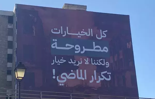 A sign on the facade of a building in the Tabaris area of Beirut reads, 'All options are on the table, but we do not want a repeat of the past.' The sign is part of a campaign to keep Lebanon out of the Gaza war. [Nohad Topalian/Al-Fassel]