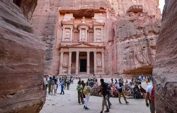 Visitors tour near the Treasury at the ruins of the ancient Nabatean city of Petra in southern Jordan on December 12, 2022. Petra drew 900,000 visitors last year, close to the previous record of one million set in 2019. Now, the Israel-Hamas war threatens to undo those gains. [Khalil Mazraawi/AFP]