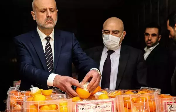 Lebanon's Interior Minister Bassam al-Mawlawi (left) checks one of the fake oranges filled with Captagon pills and concealed in boxes containing real fruit, after the shipment was intercepted by the customs and the anti-drug brigade at the Beirut port on December 29, 2021. [Anwar Amro/AFP]