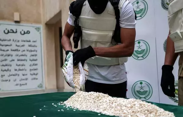 An officer of the Directorate of Narcotics Control of Saudi Arabia's Interior Ministry sorts through tablets of Captagon seized during a special operation, on March 1, 2022. [Fayez Nureldine/AFP]