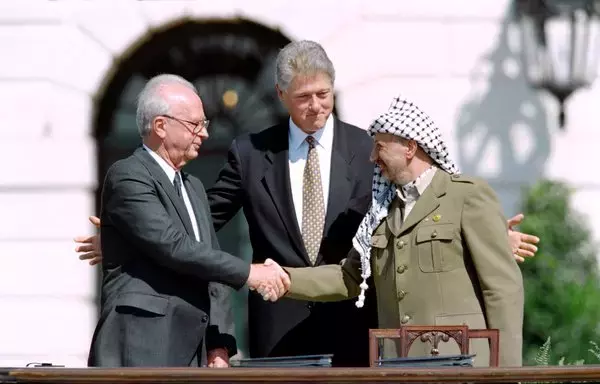 US President Bill Clinton stands between Palestine Liberation Organization leader Yasser Arafat and Israeli Prime Minister Yitzahk Rabin as they shake hands for the first time on September 13, 1993, at the White House, after signing the historic Oslo Accords. [J. David Ake/AFP]