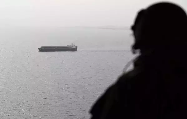 A picture taken on August 10, 2018, shows an Emirati soldier watching from a military plane a ship crossing Bab al-Mandeb strait at the southern entrance to the Red Sea. [Karim Sahib/AFP]