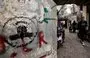 
A woman walks along an alley near graffiti showing the logo of the Palestinian Islamic Jihad (PIJ) movement at the Shatila camp for Palestinian refugees in the southern suburb of Beirut on November 7, amid ongoing battles between Israel and the Palestinian terrorist group Hamas in Gaza. [Ahmad al-Rubaye/AFP]        