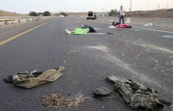 Bodies lie on a main road near the Gevim Kibbutz, close to the border with Gaza, on October 7, following Hamas's terror attack on Israel. [Oren Ziv/AFP]