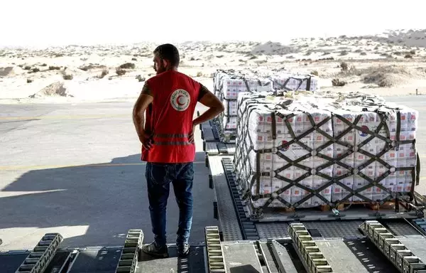 A member of the Egyptian Red Crescent stands next to a shipment of humanitarian aid bound for Gaza unloaded from a Qatari military transport aircraft at al-Arish airport in Egypt's North Sinai province on November 9, 2023. [Karim Jaafar/AFP]