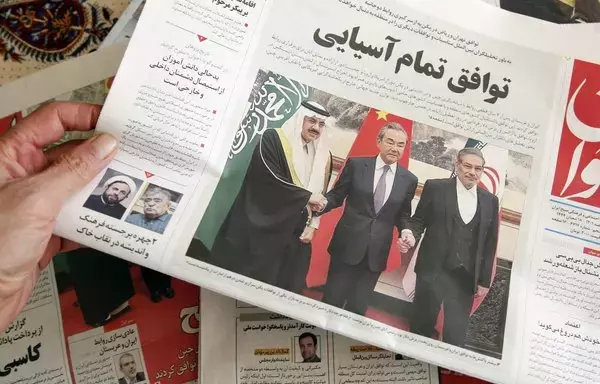 رجل في طهران يحمل صحيفة محلية تتحدث على صفحتها الأولى عن الاتفاق الذي توسطت فيه الصين بين إيران والمملكة العربية السعودية لإعادة العلاقات بين البلدين، والذي تم التوقيع عليه في بيجين في اليوم السابق، 11 آذار/مارس 2023. فشلت الصين في إدانة الهجمات التي شنها الحوثيون المدعومين من إيران على السفن في البحر الأحمر، والتي عطلت التجارة العالمية. [عطا كيناري/وكالة الصحافة الفرنسية]