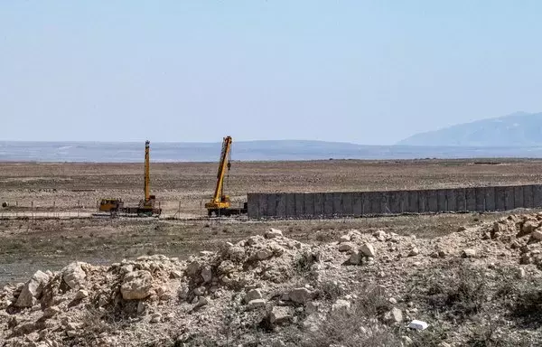 This picture taken on March 29, 2022 from the countryside near Syria's town of al-Hol in the northeastern al-Hasakeh province shows a view of the concrete border fence being erected on the Iraqi side of the border. [Delil Souleiman/AFP]