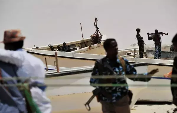 Armed militiamen and some pirates stand among fishing boats on the coast in the central Somali town of Hobyo on August 20, 2010. [Roberto Schmidt/AFP]