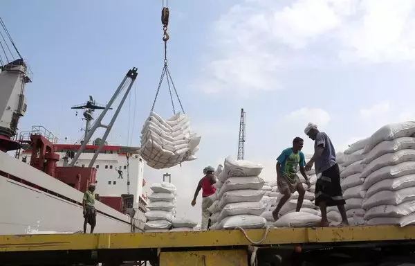 عمال يفرغون حمولة مساعدات القمح المقدمة من اليونيسف من سفينة شحن في ميناء الحديدة على البحر الأحمر في عام 2018. [عبدو حيدر/ وكالة الصحافة الفرنسية]