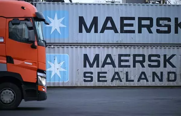 A truck driver makes his way past containers with the logo of Danish shipping giant Maersk and Maersk Sealand stacked at a transshipment station in western Germany, on January 23. [Kirill Kudryavtsev/AFP]