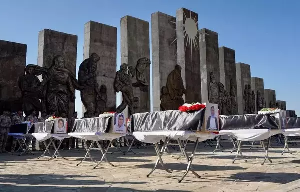 People attend a funeral ceremony for the remains of 41 victims from the Yazidi minority, who were executed by ISIS in 2014, in front of a memorial monument in the Ninawa province district of Sinjar, on January 24. [Zaid al-Obeidi/AFP]